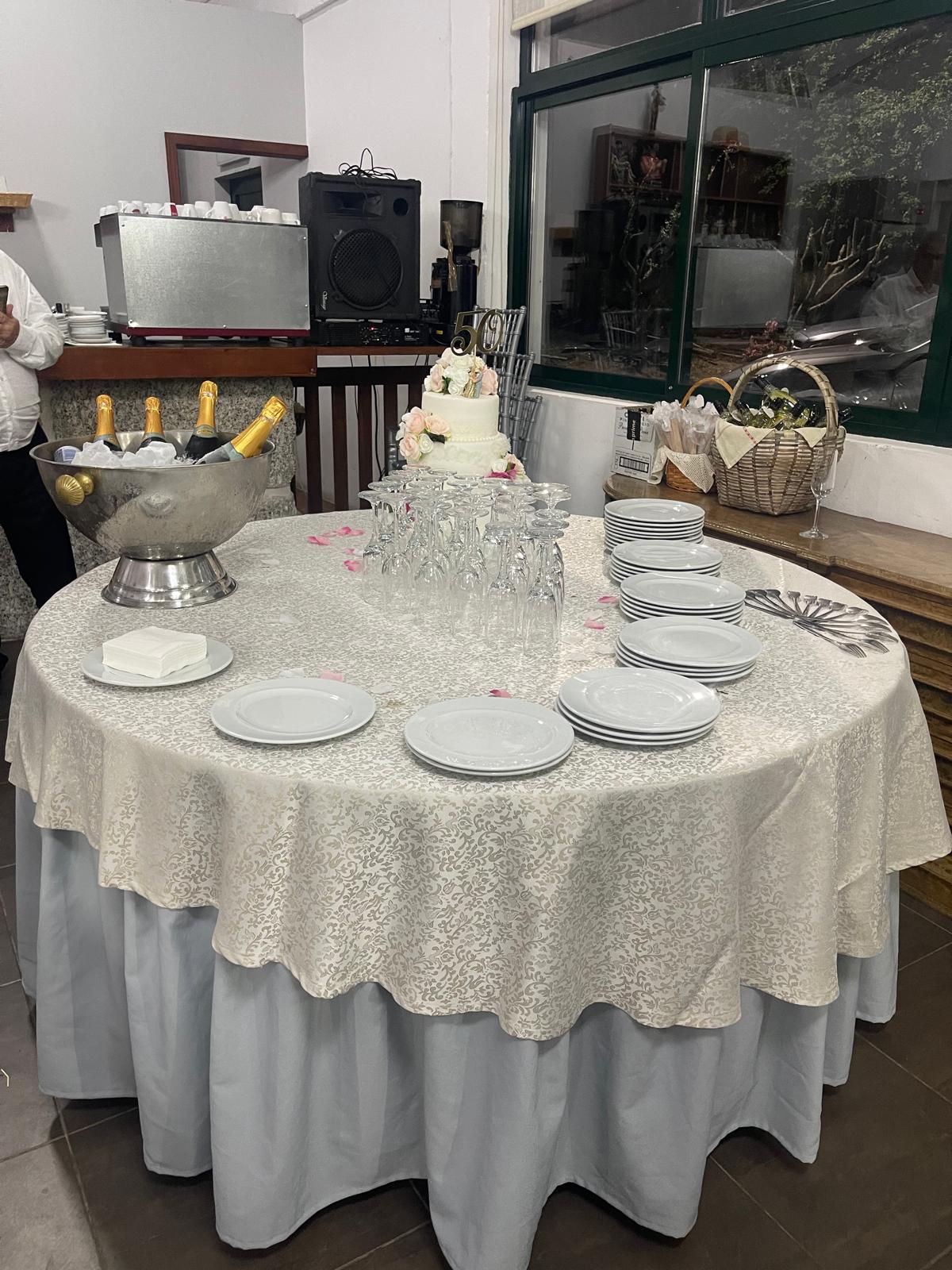 Mesa redonda preparada para receber convidados, com pratos e copos